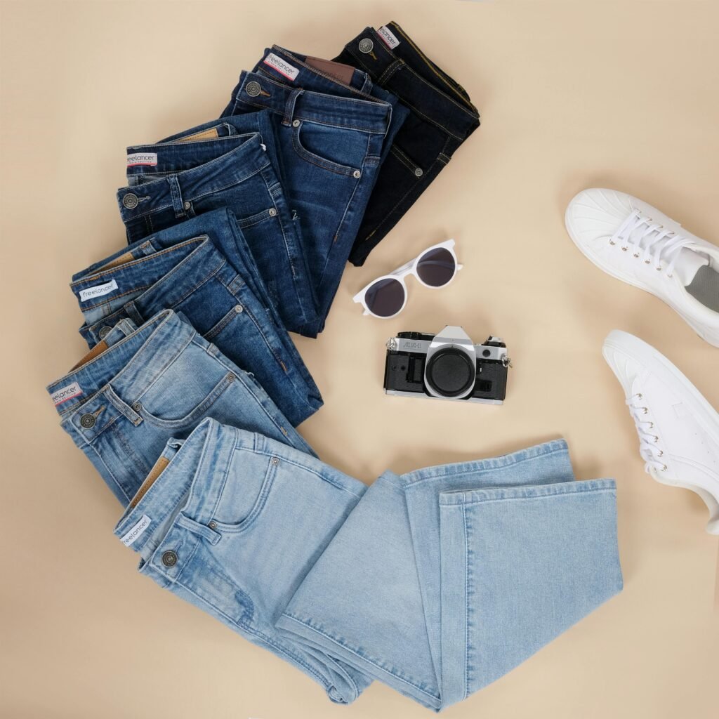 pexels-photo-18533668-18533668 Flat lay showcasing various denim jeans, sneakers, sunglasses, and a camera.