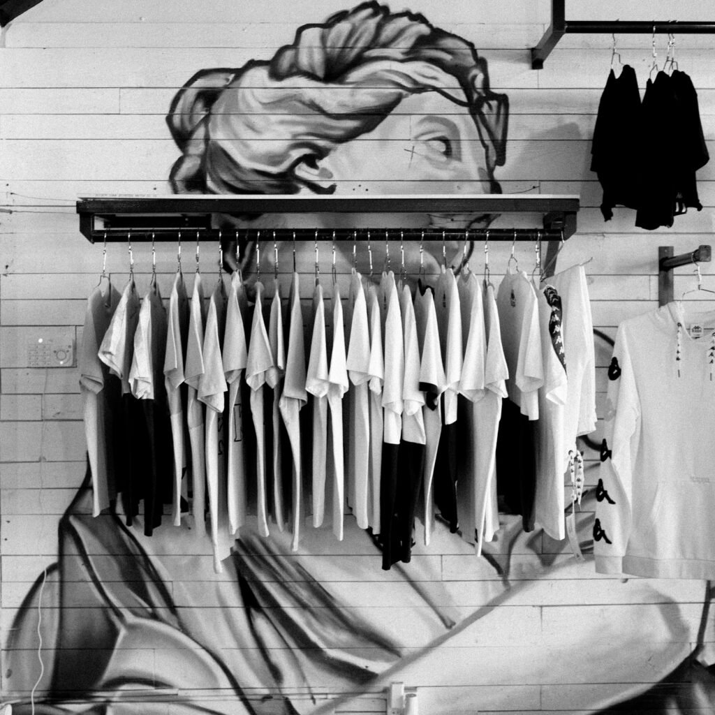pexels-photo-5771897-5771897 Monochrome display of clothing on a rack against a graffiti background.
